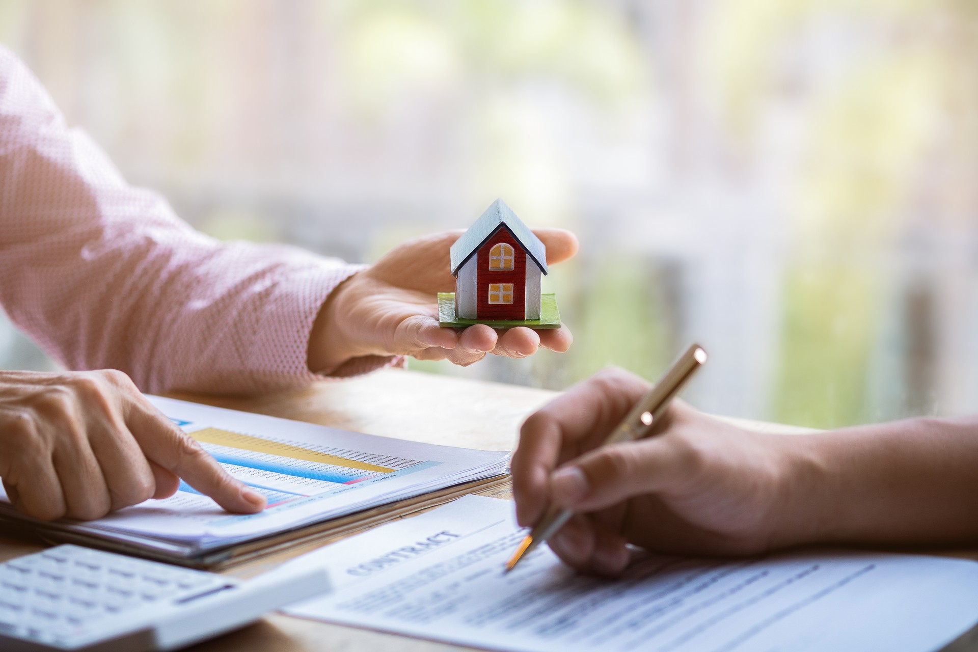 Estate agent pointing finger on document showing total cost. Signing a paper document for buying house.Real estate, home loan and insurance concept.